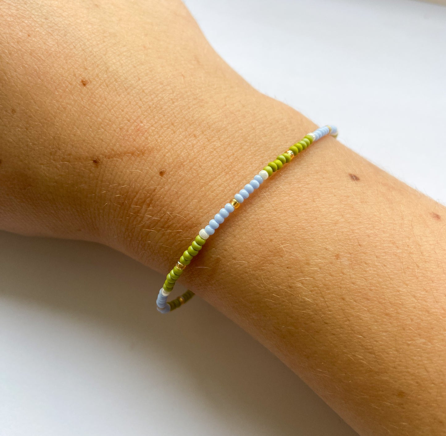 Dainty miyuki bead bracelet in green and blue with gold detail